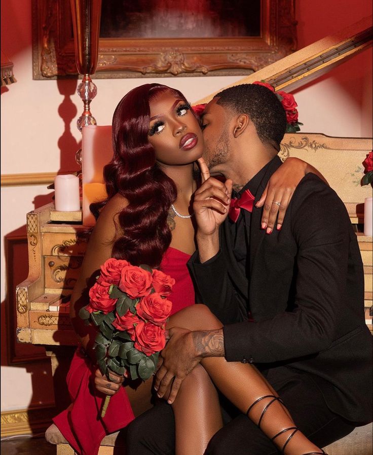 a man and woman sitting next to each other on a chair with flowers in their lap