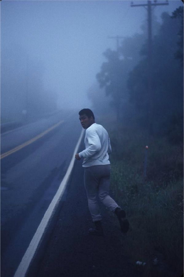 a man is running down the road in the foggy night with his jacket on