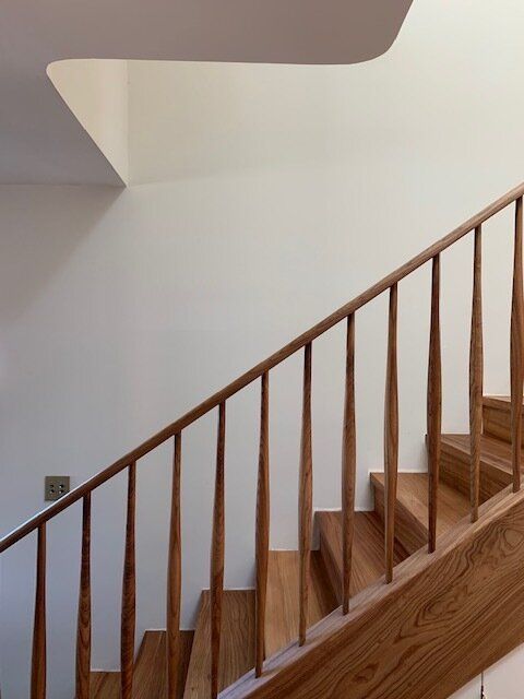 a wooden stair case next to a white wall