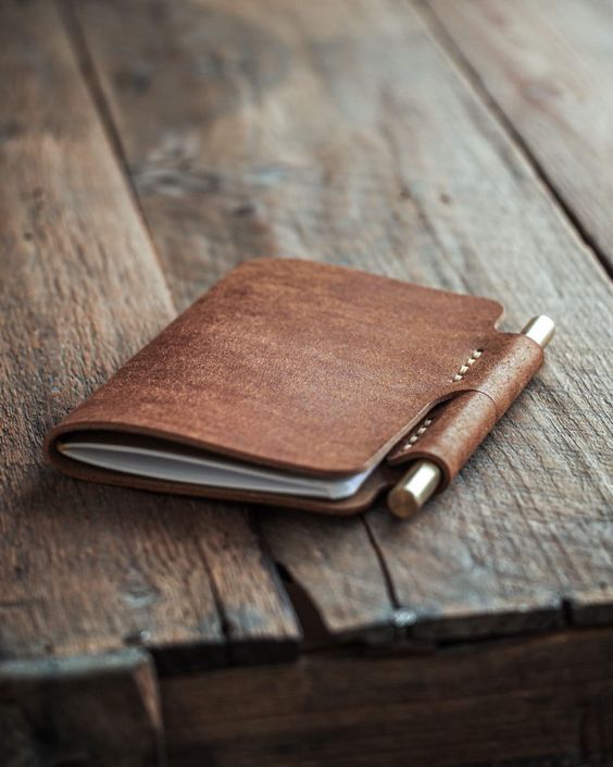 a brown leather notebook sitting on top of a wooden table