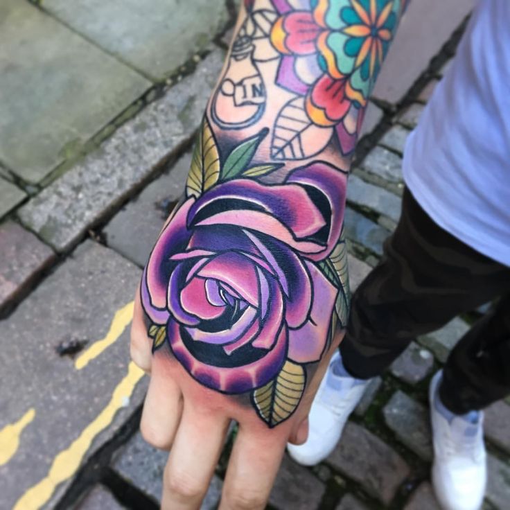 a person with a tattoo on their arm holding a rose in the middle of his hand