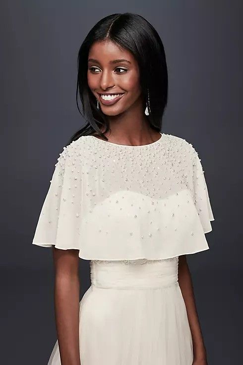 a woman wearing a white dress and smiling at the camera with her hands in her pockets