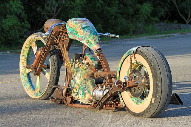 an unusual looking motorcycle sitting in the middle of the road with trees in the background