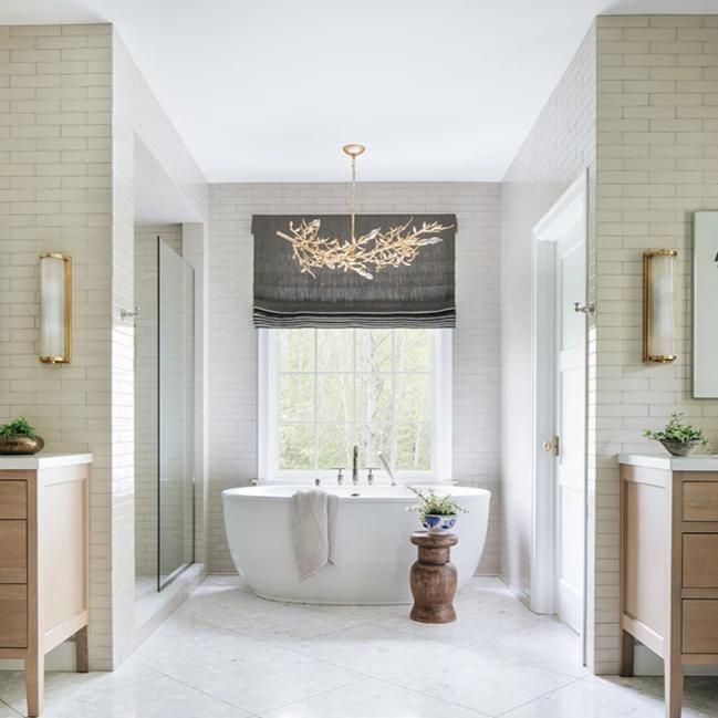 a white bath tub sitting under a window next to a sink in a room with two windows