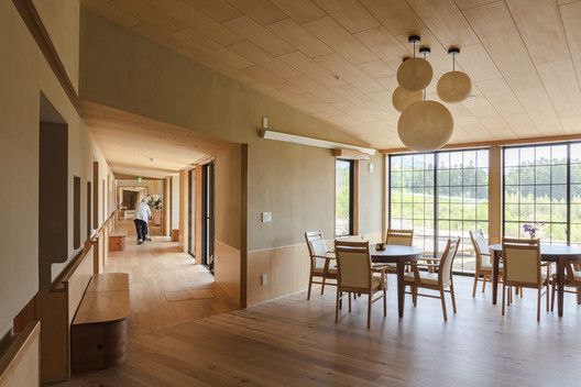 an empty dining room with wooden floors and large windows on the side of the wall