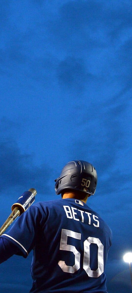 a baseball player holding a bat on top of a field at night with lights in the background