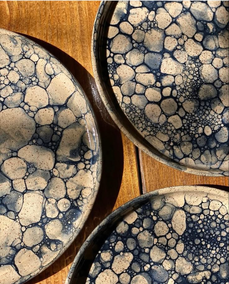 three blue and white plates sitting on top of a wooden table