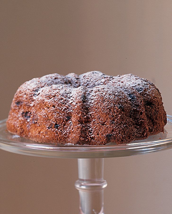 a bundt cake on a glass plate next to a bowl of icecream