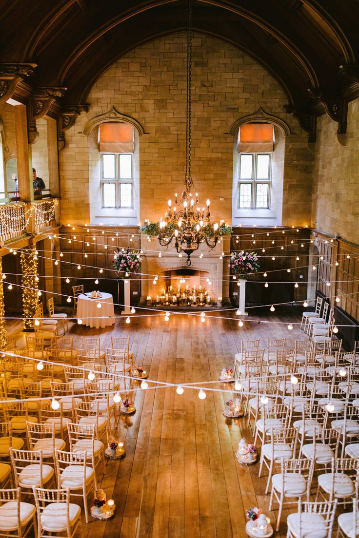 an indoor venue with rows of chairs and candles on the floor, surrounded by string lights