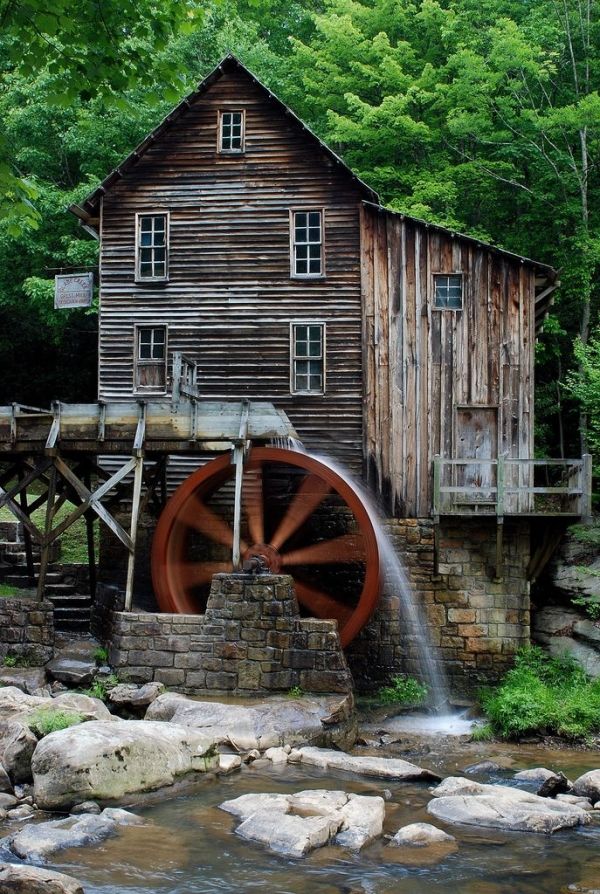 an old mill and water wheel in the woods