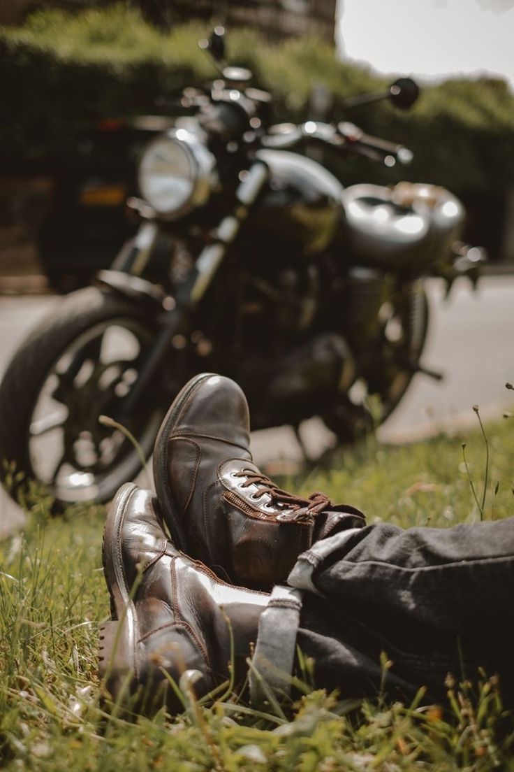 a pair of shoes sitting in the grass next to a motorcycle