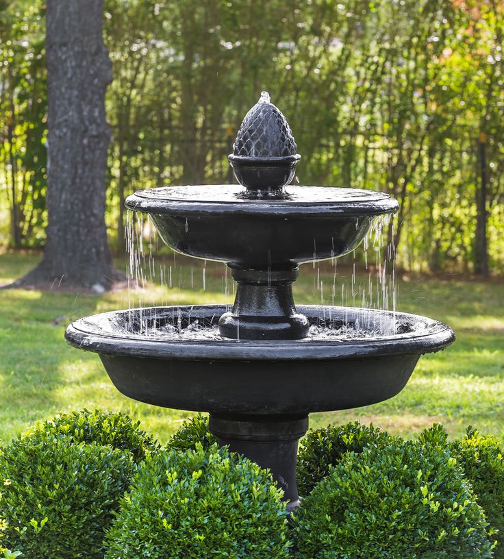 a water fountain in the middle of some bushes