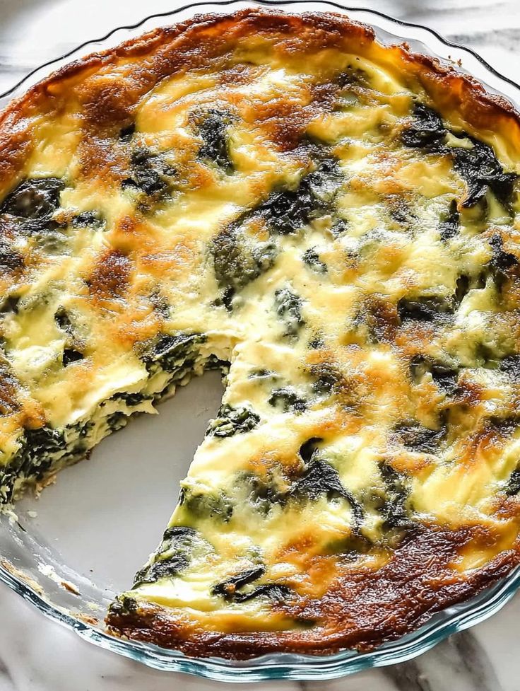 a cheese and spinach quiche on a plate with one slice missing from it