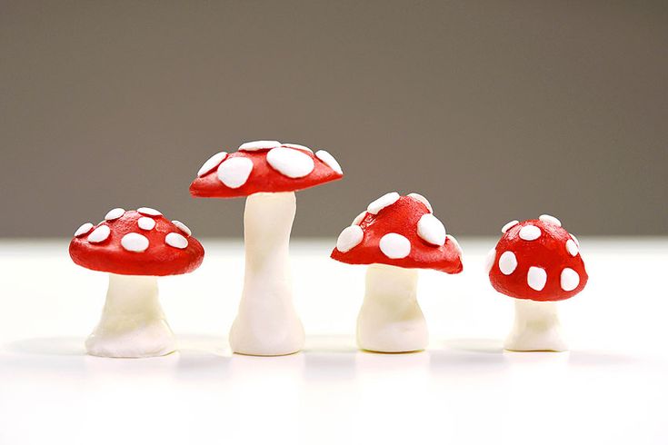 small red mushrooms with white dots on them sitting in the middle of a table top