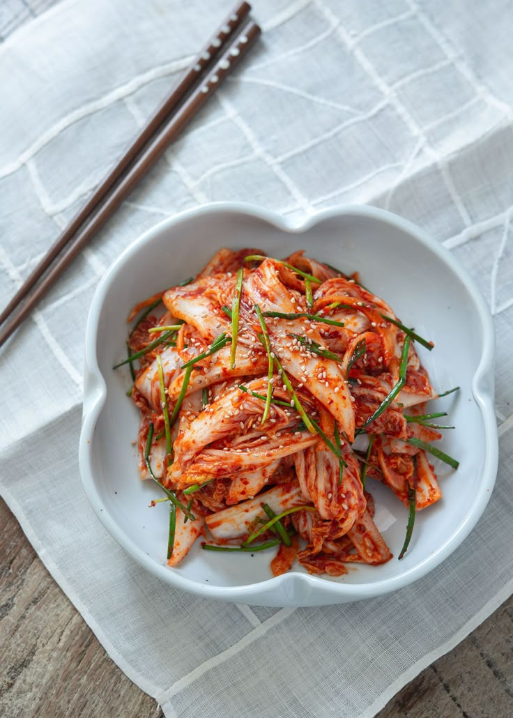 a white bowl filled with food next to chopsticks on top of a table