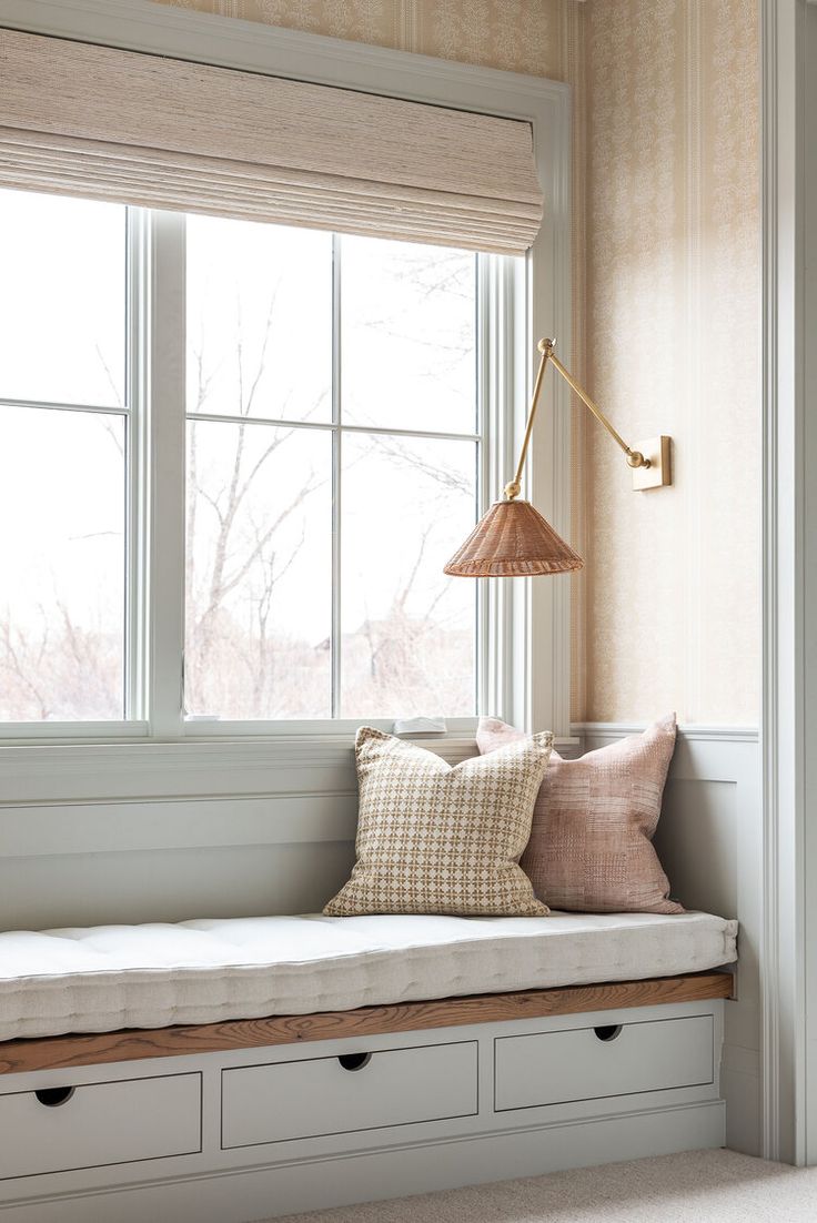 a window seat with pillows and a lamp