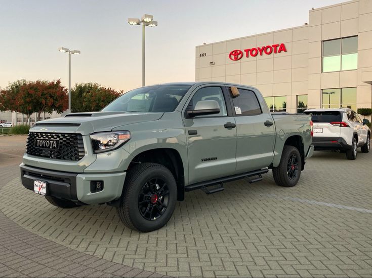 a gray toyota tundra is parked in front of a toyota dealership with other vehicles