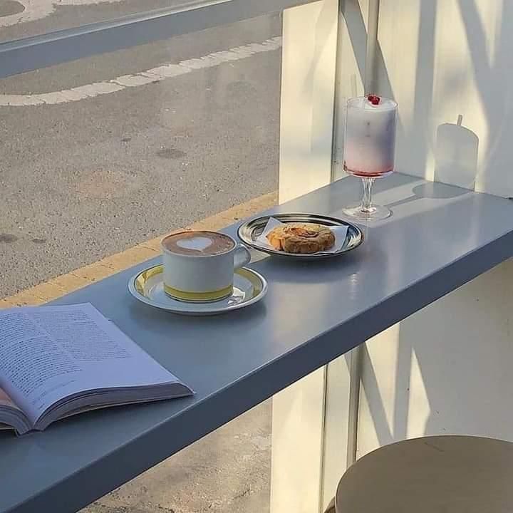 an open book on a table next to a cup of coffee and a plate of food