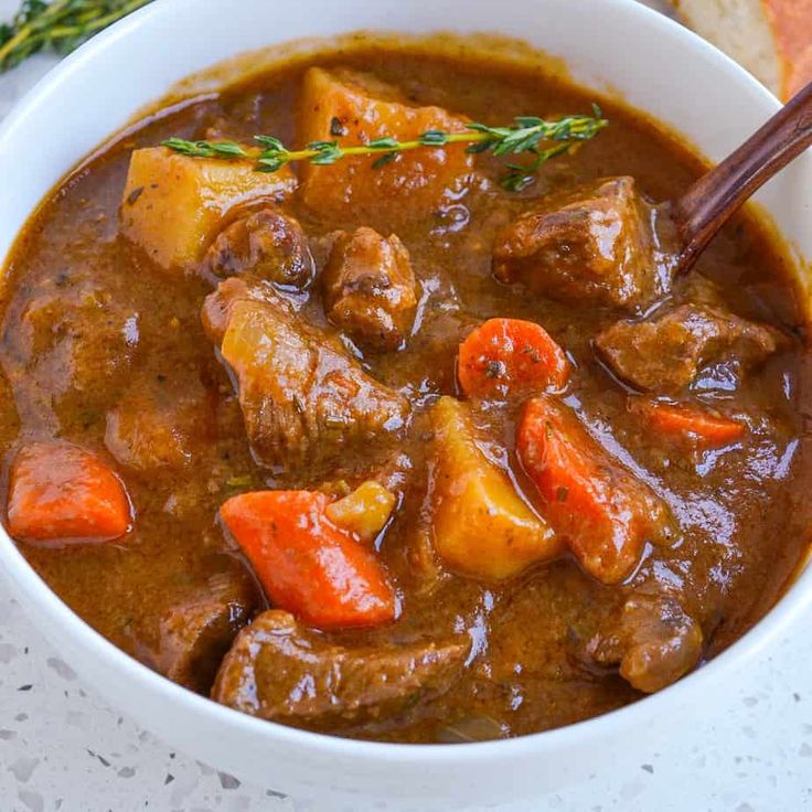 a bowl of stew with carrots, potatoes and meat in it on a table