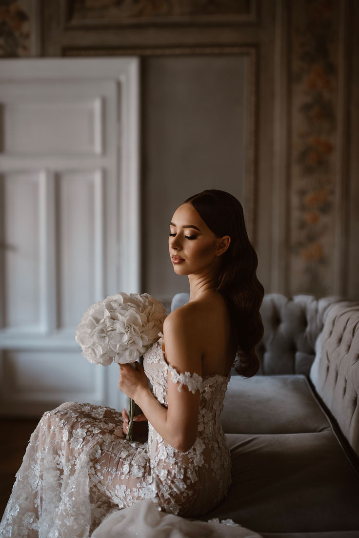 a woman sitting on top of a couch holding a bouquet