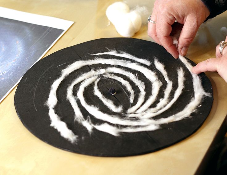 someone is making something out of paper on a table with other items around it and the person has their hand in the center of the circle