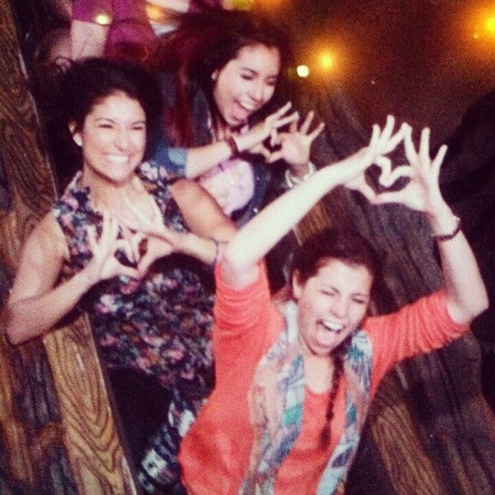 four girls are posing for the camera with their hands in the air