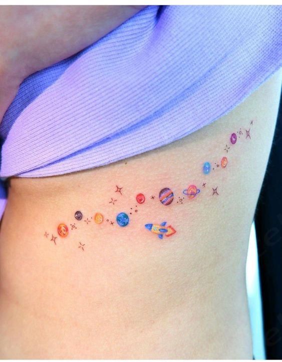 a woman's stomach with planets and stars tattoo on her side ribcage