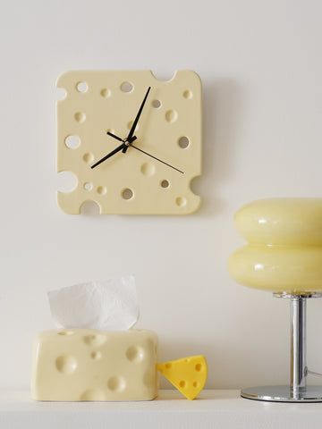 a white wall clock sitting on top of a shelf next to a yellow chair and table