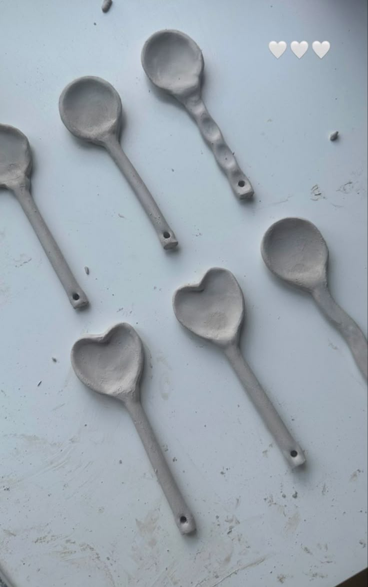 six spoons are arranged in the shape of hearts on a white surface with heart - shaped holes