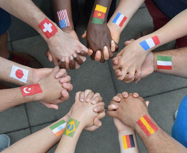 a group of people with their hands painted in different colors and country flags are standing in a circle