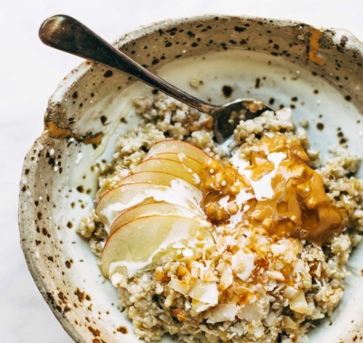 a bowl filled with oatmeal and apples on top of a white table