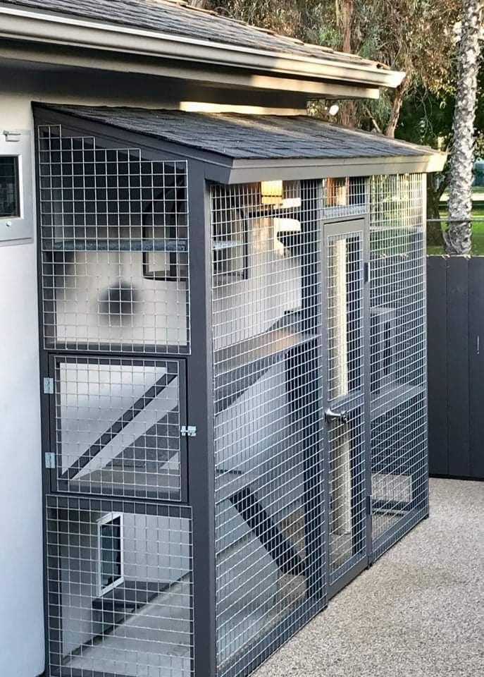 a metal structure with a door and some stairs on it's side in front of a building