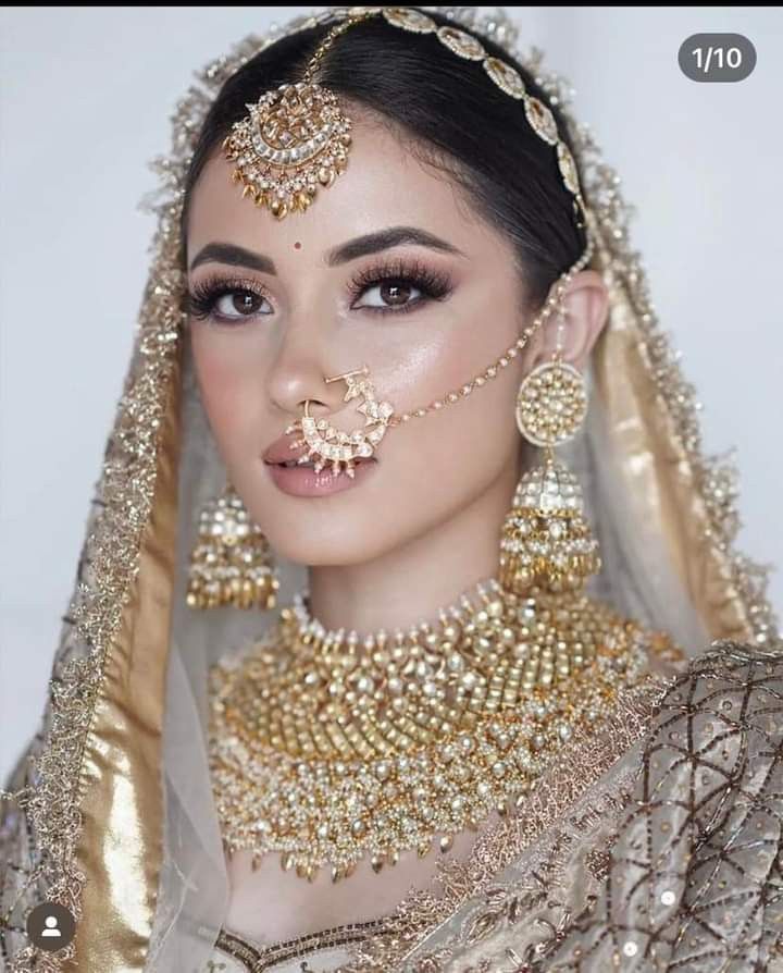 a woman wearing gold jewelry and veil with her nose ring in front of her face