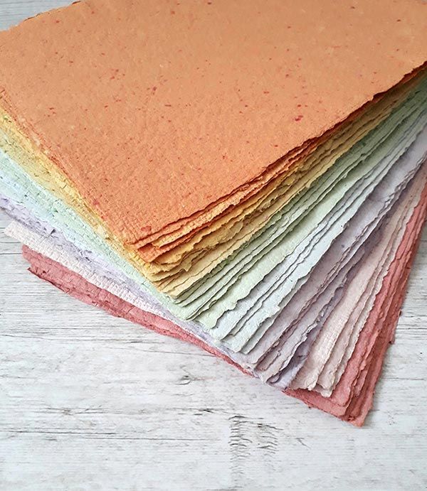 a stack of different colored papers sitting on top of a wooden table next to each other