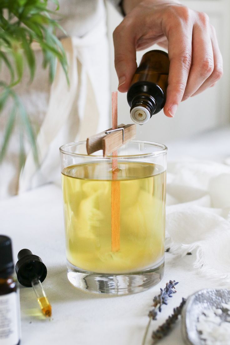 a person is pouring an orange juice into a glass with a wooden stick in it