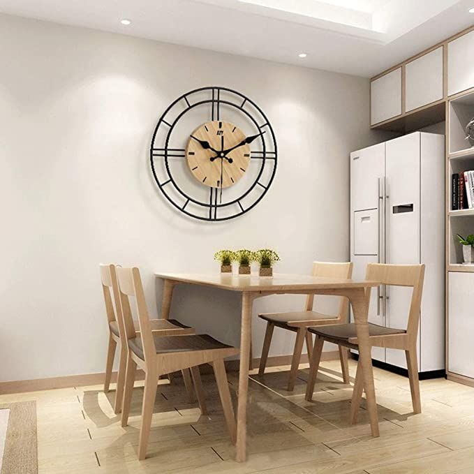 a clock mounted to the side of a wall next to a table with four chairs