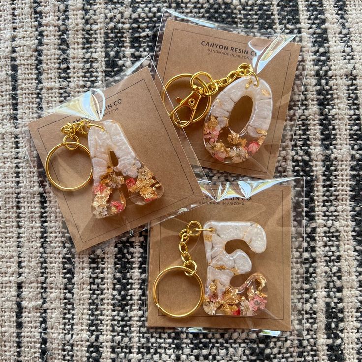 three pieces of jewelry are sitting on top of a piece of brown paper with the letter s in it