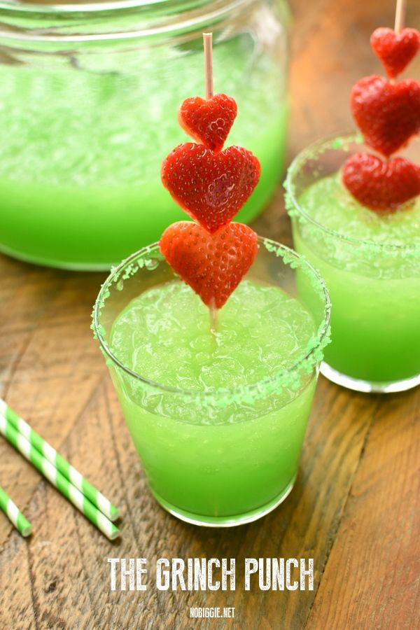 two glasses filled with green liquid and strawberries on the top one has red heart shaped strawberries