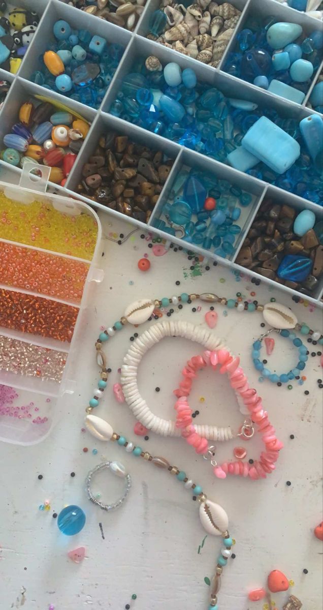 various beads and bracelets are arranged in bins on a table next to each other