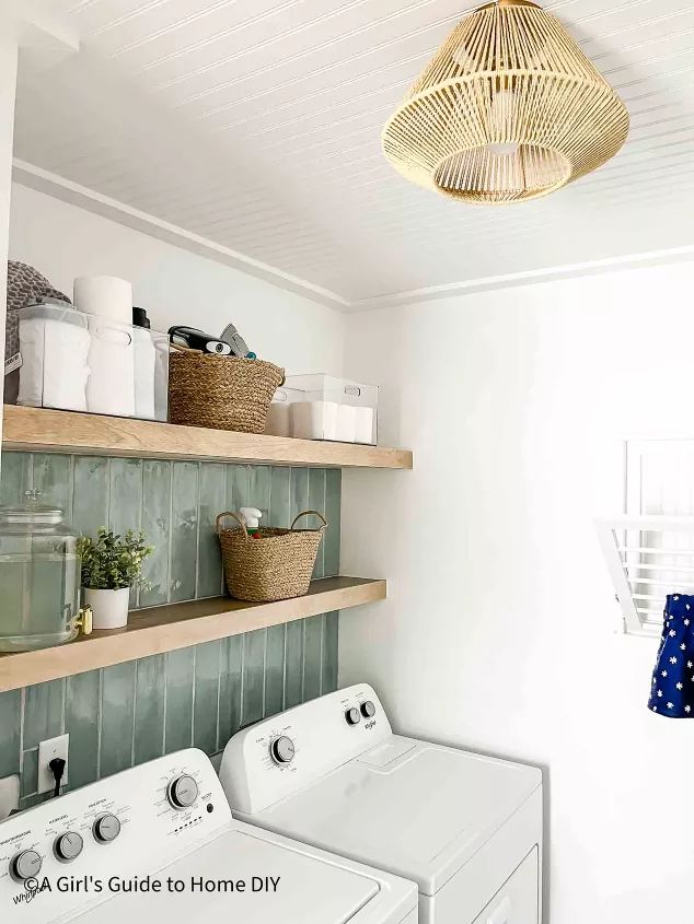 a washer and dryer in a small room with open shelves on the wall