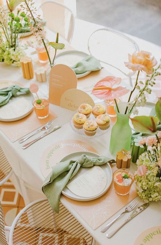 the table is set with cupcakes, flowers and napkins for guests to eat