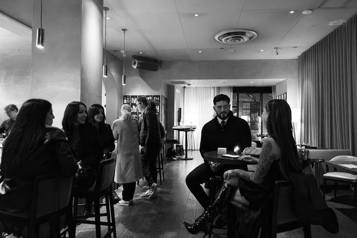 black and white photograph of people sitting at tables in a restaurant with candles on the table