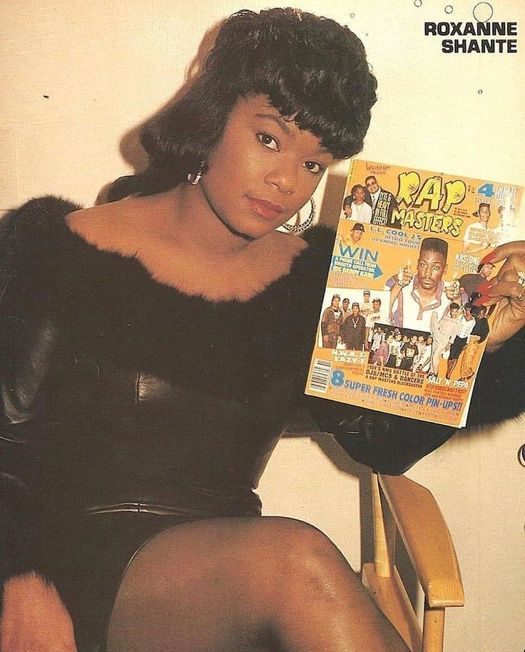 a woman sitting in a chair holding up a magazine