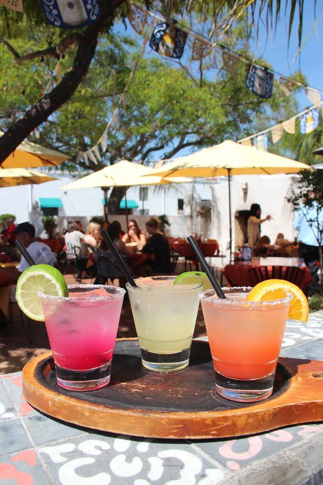 three different colored drinks sitting on top of a wooden tray