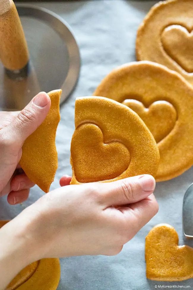 someone is holding up some heart shaped cookies with the words dalgon korean sugar candy