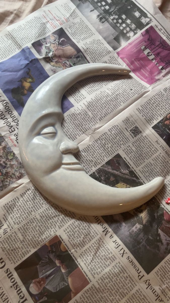 a fake moon with a face on top of it next to a newspaper page and scissors