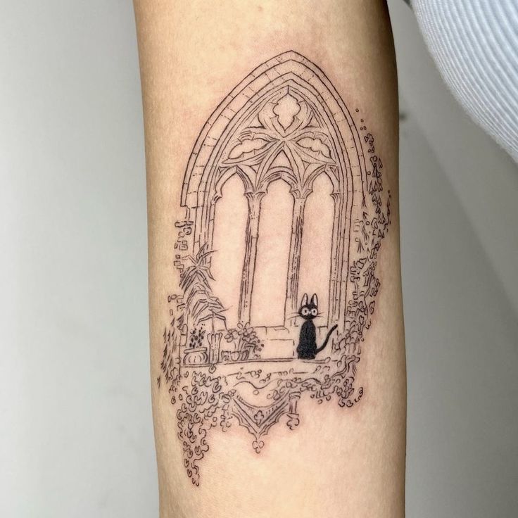 a woman with a cat tattoo on her arm and leg is standing in front of an arched window