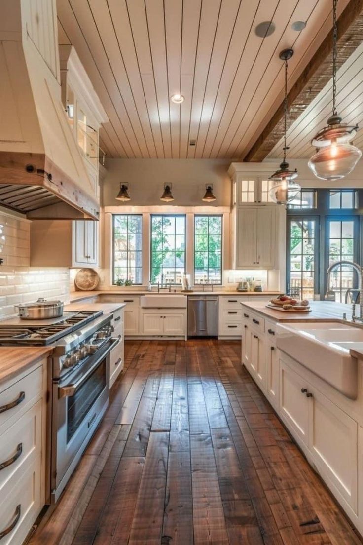 a large kitchen with wooden floors and white cabinetry on the walls, along with an island in the middle