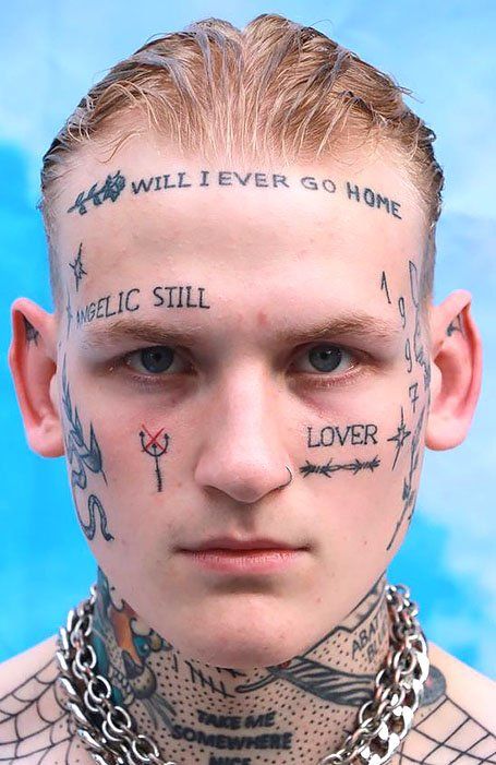 a man with tattoos on his face and neck is looking at the camera while wearing chain around his neck