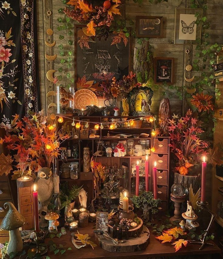 a table topped with lots of candles next to a wall covered in pictures and plants